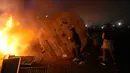 Demonstran menggulung gulungan kabel kayu ke barikade yang terbakar saat protes RUU Pensiun di Paris, Prancis, Jumat (17/3/2023). (AP Photo/Lewis Joly)