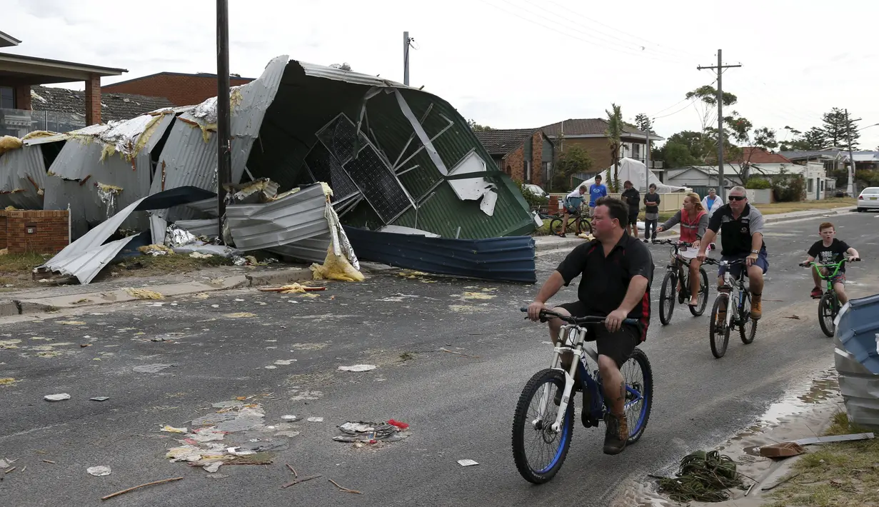 Warga bersepeda sambil mengamati kerusakan dari sebuah rumah akibat badai tornado yang langka di Kurnell pinggir Sydney, Rabu (16/12). Badai dengan hujan es disertai angin berkekuatan sampai 200 km per jam melanda kawasan tersebut. (REUTERS/Jason Reed)