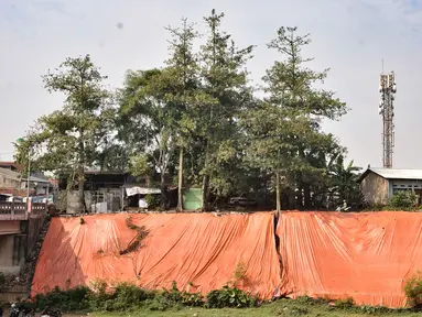 Terpal besar menutupi lokasi tanah longsor di pinggir Kanal Banjir Timur, Jakarta, Kamis (18/6/2020). Longsor yang terjadi pada awal Januari 2020 tersebut belum diperbaiki dan hanya ditutupi terpal besar guna mengantisipasi longsor susulan. (merdeka.com/Iqbal S. Nugroho)