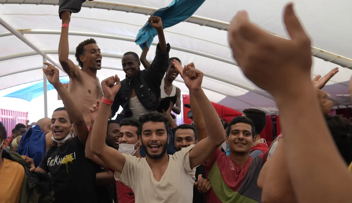 Para migran merayakan di dek kapal penjaga pantai LSM Spanyol Open Arms setelah pengumuman dari kru bahwa Italia telah memberikan akses kapal untuk berlabuh di pelabuhan, setelah operasi penyelamatan di zona perairan internasional di laut Mediterania, Rabu, 21 September 2022. (AP/Petros Karadjias)