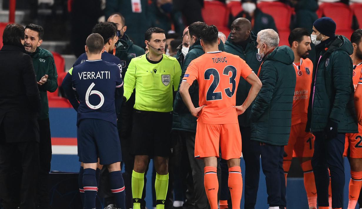 Wasit Ovidiu Hategan berbicara dengan ofisial tim istanbul Basaksehir usai dihentikannya laga lanjutan Liga Champions Grup H melawan Paris Saint-Germain di Parc des Princes Stadium, Selasa (8/12/2020). (AFP/Franck Fife)