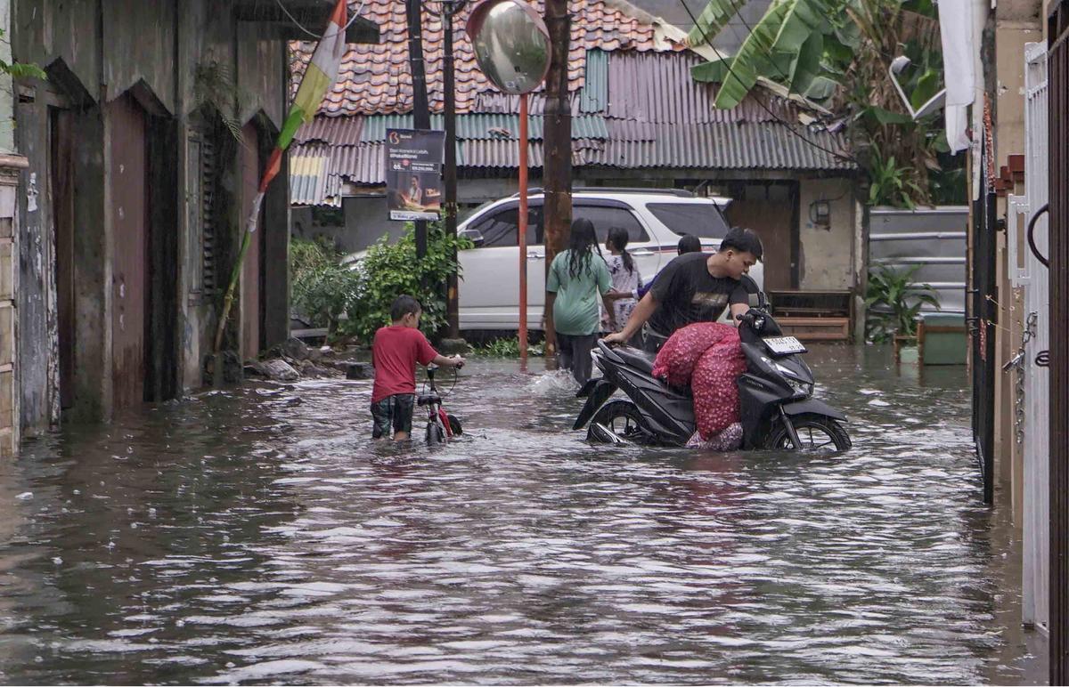 FOTO: Drainase Meluap, Warga Pasar Rebo Terobos Genangan