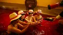 Seorang pria menuangkan anggur ke dalam tangan seorang wanita saat mereka duduk dalam air panas dengan air berwarna anggur di resor spa Hakone Kowaki-en Yunessun saat acara menandai Beaujolais Nouveau Day,Tokyo, Jepang (19/11). (REUTERS/Thomas Peter)