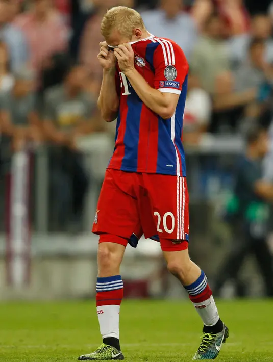 Gelandang Muenchen, Sebastian Rode menutup mukanya dengan kaos usai timnya gagal melaju ke final Liga Champions di Allianz Arena, Jerman (12/5/2015). Muenchen menang 3-2 atas Barcelona di leg kedua semifinal liga Champions. (Reuters/Ina Fassbender)
