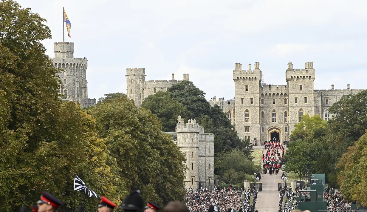Para pelayat menyaksikan State Hearse of Queen Elizabeth II saat berkendara di sepanjang Long Walk menjelang Committal Service untuk Ratu Elizabeth II pada Senin, 19 September 2022 di Windsor, Inggris. (Stuart C. Wilson/Pool Photo via AP)