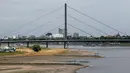 <p>Sebuah kapal pedalaman berlayar di Rhine saat orang-orang berdiri di pantai di tepi sungai yang sebagian mengering di Duesseldorf, Jerman barat (25/7/2022). Keringnya sungah Rhine akibat Eropa mengalami gelombang panas. (AFP/Photo/Ina Fassbender)</p>