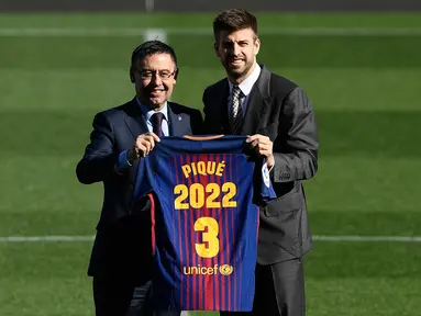 Bek Spanyol, Gerard Pique dan Presiden Barcelona FC, Josep Maria  berpose memegang jersey Barcelona pada pengumuman perpanjangan kontraknya di stadion Camp Nou, Senin (29/1). Pique memperpanjang kontraknya bersama Barcelona hingga 2022. (LLUIS GENE/AFP)