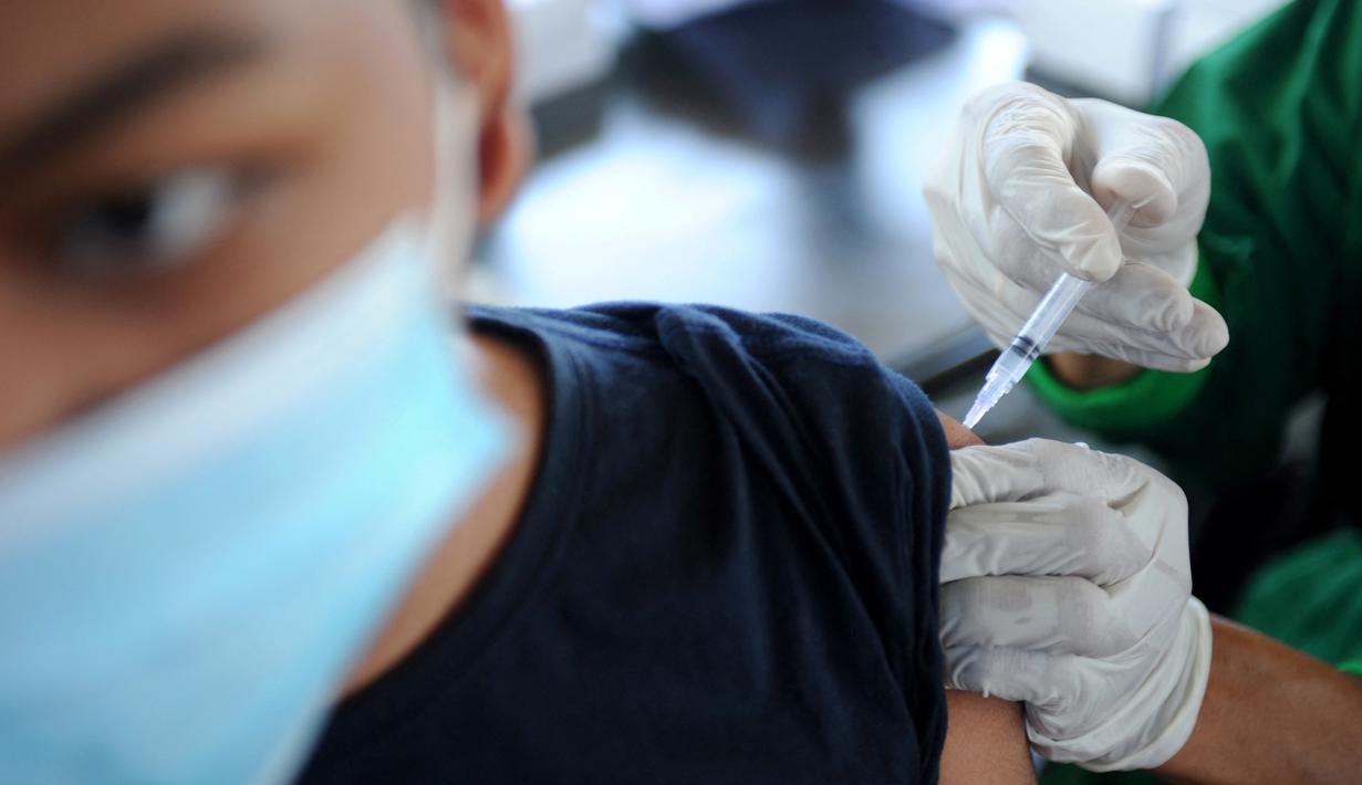 Seorang pemuda menerima vaksin virus corona COVID-19 AstraZeneca di klinik vaksinasi massal darurat di Denpasar, Bali, Selasa (6/7/2021). Indonesia tengah memerangi gelombang infeksi baru yang belum pernah terjadi sebelumnya. (SONNY TUMBELAKA