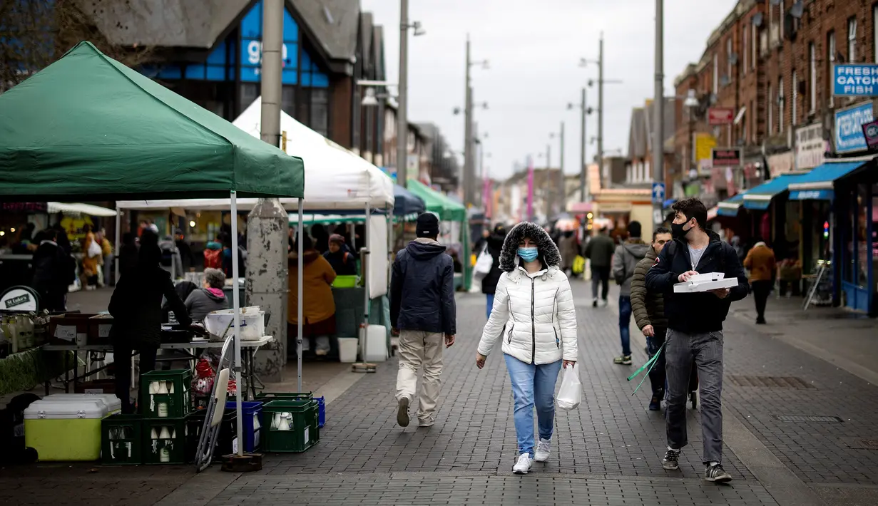 Pembeli berjalan melewati kios di pasar di Walthamstow, London timur pada 13 Februari 2022. Angka inflasi Inggris tembus 5,4 persen pada Desember lalu. Inflasi itu juga menjadi yang tertinggi dalam 30 tahun terakhir. (Tolga Akmen / AFP)