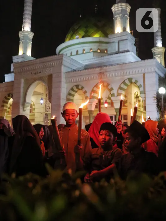 Anak-anak membawa obor sambil berkeliling kampung di kawasan Kota Tangerang, Banten, Jumat (29/7/2022) malam. Pawai obor tersebut digelar untuk menyambut malam pergantian Tahun Baru Islam atau 1 Muharam 1444 H. (Liputan6.com/Angga Yuniar)