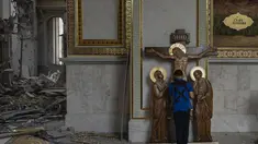 Seorang anak laki-laki mencium patung Yesus saat membantu membersihkan Katedral Transfigurasi Odesa setelah gereja rusak berat akibat serangan rudal Rusia di Odesa, Ukraina, Minggu, 23 Juli 2023. (AP Photo/Jae C. Hong)