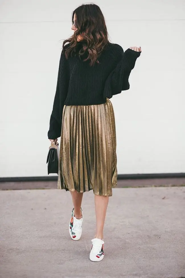 Buat penampilan kamu terlihat unik dan berbeda dengan memakai black sweater and gold pleated skirt, lalu pakai sneakers putih. (sumber foto: hellofashionblog.com/pinterest)