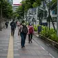 Pekerja kantoran berjalan di trotoar Jalan Sudirman, Jakarta Pusat, Rabu (6/1/2021). Selama pembatasan sosial berskala besar (PSBB) di wilayah Jawa dan Bali pada 11-25 Januari 2021, aktivitas bekerja di kantor diperketat dengan sistem work from home (WFH) 75 persen. (Liputan6.com/Faizal Fanani)