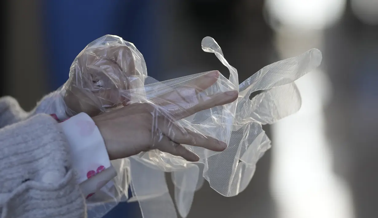Pengunjung memakai sarung tangan plastik setibanya di ruang pameran di Goyang, Korea Selatan, Sabtu (4/12/2021). Korsel juga mengonfirmasi tiga lagi kasus varian omicron baru ketika para pejabat berebut untuk memperketat jarak sosial dan kontrol perbatasan. (AP Photo/Lee Jin-man)