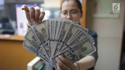 Teller menunjukkan mata uang dolar di Jakarta, Jumat (2/2). Dengan nilai tersebut posisi nilai tukar rupiah sudah masuk level undervalued, atau telah keluar dari level fundamentalnya. (Liputan6.com/Angga Yuniar)