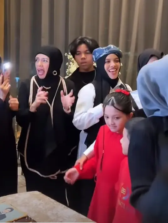 Ia mengenakan atasan lengan panjang dengan vest hitam outliner nude beserta hijab [@genifaruk]