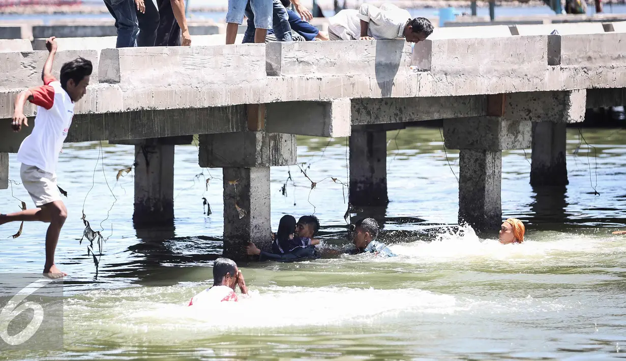 Warga melompat kelaut berusaha menolong anak kecil yang terjatuh ke laut di dermaga Muara Angke, Jakarta (24/3). Akibat kelalaian ibunya seorang anak tercebur ke laut dan langsung di selamatkan warga dan prajurit TNI AL. (Liputan6.com/Faizal Fanani)