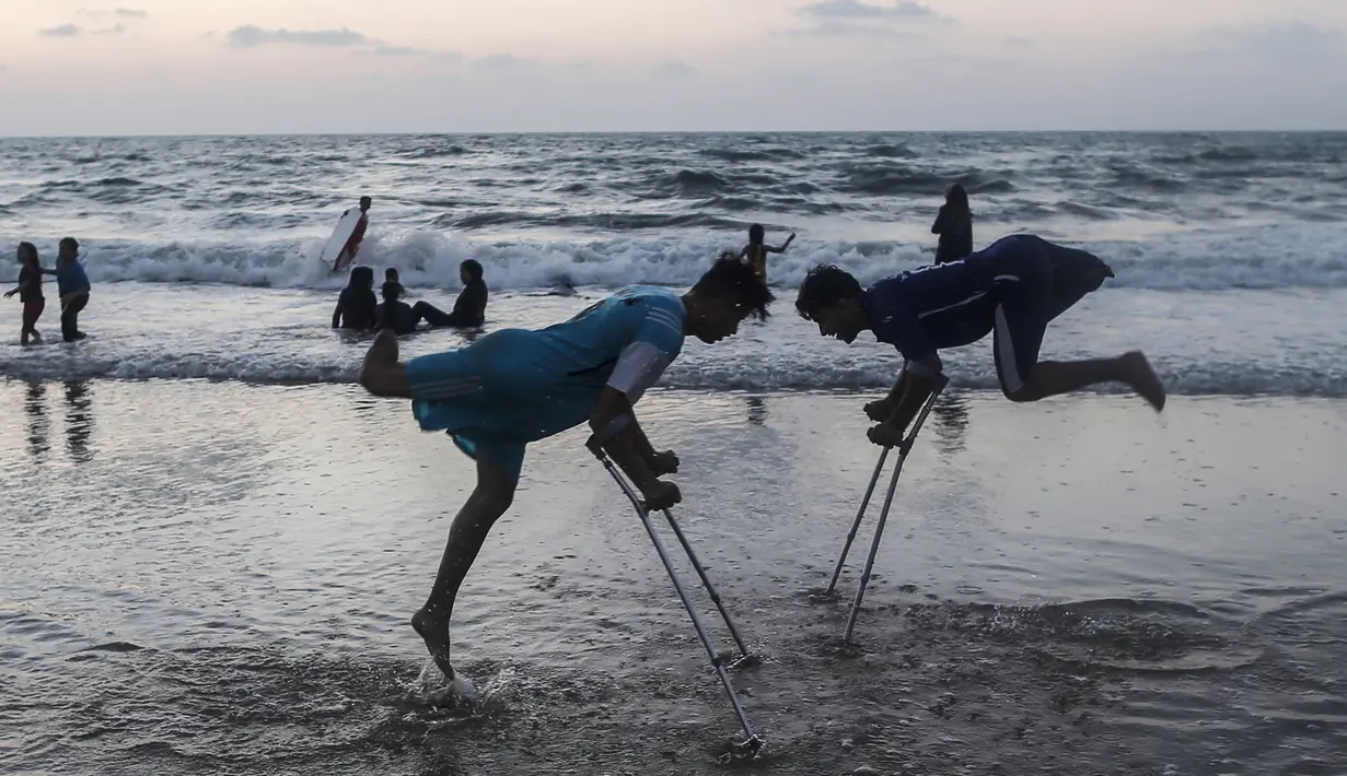 Dua pemuda Palestina Mohammed Eliwa (kiri) dan Ahmed al-Khoudari melakukan pemanasan sebelum bermain sepak bola di pantai di Kota Gaza (20/9/2019). Eliwa 17 tahun dan Ahmed al-Khoudari 20 tahun kehilangan satu kakinya saat bentrok di perbatasan Israel. (AFP Photo/Mahmud Hams)