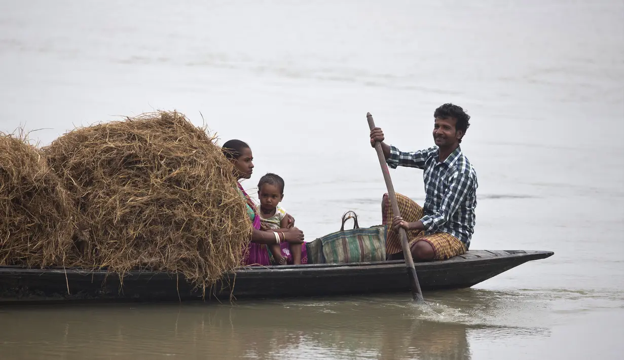 Keluarga membawa jerami untuk ternak mereka di atas kapal ketika mereka menyeberangi sungai Brahmaputra di desa Kasoshila di pinggiran Gauhati, India (21/10/2019).  (AP Photo/Anupam Nath)