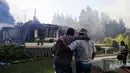 Dua orang pria menyaksikan sisa-sisa api yang membakar rumah mereka di Concepcion, Chili (26/1). Dalam peristiwa ini tidak ada korban jiwa. (Alejandro Zonez/Aton via AP)