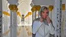 Istri Presiden Prancis, Brigitte Macron merapikan penutup kepalanya saat mengunjungi Masjid Sheik Zayed di Abu Dhabi, Kamis (9/11). Di masjid itu, Brigitte terlihat mengenakan penutup kepala bermotif leopard dan melepas sepatu. (Giuseppe CACACE / AFP)