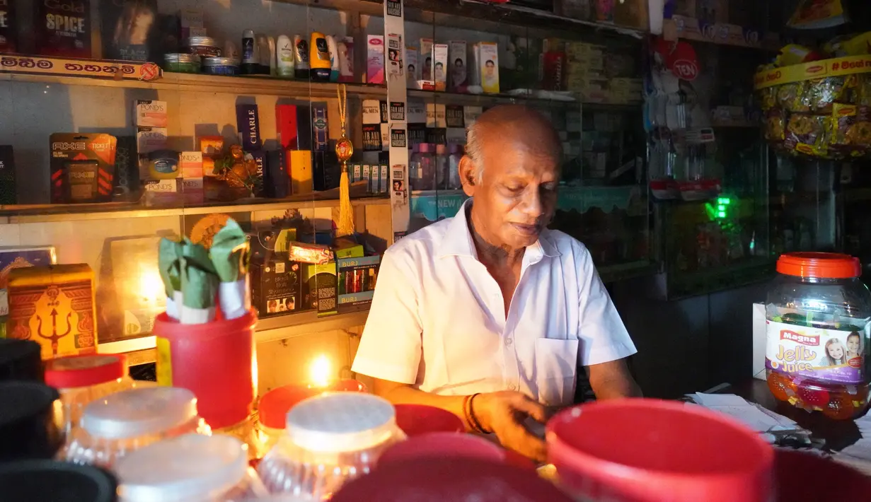 Seorang pria bekerja dengan bantuan lilin di toko miliknya di tengah pemadaman listrik di Kolombo, Sri Lanka (17/8/2020). Sri Lanka mengalami pemadaman listrik berskala nasional pada Senin (17/8) karena kerusakan teknis di sebuah pembangkit listrik di Kerawalapitiya. (Xinhua/A. Hapuarachchi)