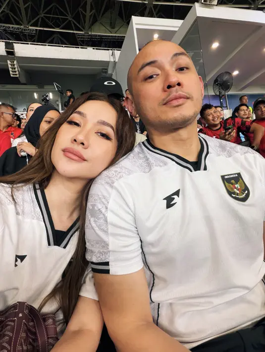 Bunga Citra Lestari dan Tiko Aryawardhana tampil kompak totalitas dengan paduan jersey putih dan celana hitam. Tas Goyard berwarna cokelat dijinjing BCL saat nobar pertandingan final [@itsmebcl]