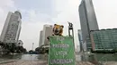 Aktivis Greenpeace membentangkan spanduk bertuliskan “Pilih Presiden Untuk Lingkungan” di Bundaran HI, Minggu (11/5/14). (Liputan6.com/Faizal Fanani)