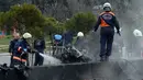 Petugas memadamkan api di sekitar lokasi terjatuhnya helikopter yang menabrak menara stasiun televisi, Turki, Jumat (10/3). Lima orang yang berada di dalamnya tewas seketika. (AP Photo)