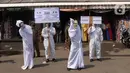 Petugas Kecamatan Larangan berkeliling mengenakan pakaian pocong saat melakukan sosialisasi di Pasar Cipadu, Kota Tangerang, Rabu (16/9/2020). Pocong ini bentuk sosialiasi agar warga memperhatikan perilaku 3M COVID, yaitu memakai masker, menjaga jarak dan mencuci tangan. (Liputan6.com/Angga Yuniar)