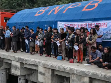 Keluarga dan warga berdoa untuk penumpang yang hilang dari kecelakaan KM Sinar Bangun di Danau Toba di Pelabuhan Tigaras, Sumatra Utara, Indonesia (21/6). KM Sinar Bangun tenggelam pada Senin (18/6) sore. (AFP Photo/Ivan Damanik)