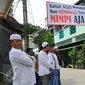 Sejumlah warga berdiri di bawah spanduk penolakan penggusuran Kampung Luar Batang, Penjaringan, Jakarta, Rabu (20/4). Mereka menolak pembongkaran tahap dua yang akan dilakukan Pemprov DKI pada Mei nanti. (Liputan6.com/Yoppy Renato)