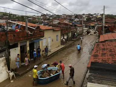 Warga membersihkan rumah mereka yang terendam banjir di Itapetinga, negara bagian Bahia, Brasil, Selasa (28/12/2021). Dua bendungan jebol pada Minggu (26/12) di timur laut Brasil, mengancam banjir yang lebih parah di wilayah yang diguyur hujan. (AP/Raphael Muller)