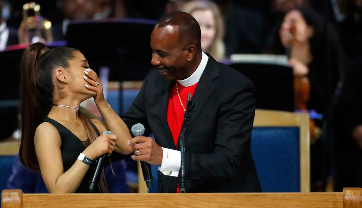 Ariana Grande tertawa bersama Uskup Charles H. Ellis III dalam upacara pemakaman Aretha Franklin di Greater Grace Temple, Detroit, Michigan, AS, Jumat (31/8). Melansir dari The Guardian, Uskup Charles meminta maaf atas tindakannya. (AP Photo/Paul Sancya)