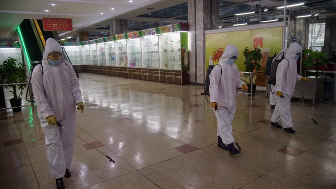 Petugas berpakaian APD melakukan penyemprotan cairan desinfektan di dalam Pyongyang Department Store No. 1, di Pyongyang, Korea Utara (28/12/2020). Protokol kesehatan diterapkan dengan melakukan desinfektan, pemeriksaan suhu tubuh hingga memakai masker. (AFP/Kim Won Jin)