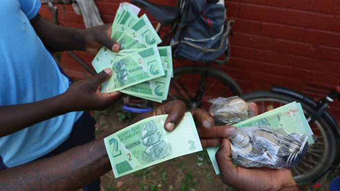 Seorang pria memegang salah satu uang kertas baru yang dikeluarkan Reserve Bank of Zimbabwe di Harare, 12 November 2019. Selama hampir sedekade terakhir, masyarakat Zimbabwe menggunakan sejumlah mata uang negara lain bertransaksi pasca krisis ekonomi yang terjadi di Afrika. (AP/Tsvangirayi Mukwazhi)