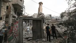 Orang-orang berdiri di antara puing-puing masjid yang hancur selama serangan udara Israel, di Kota Gaza pada 9 Oktober 2023. (Mahmud HAMS/AFP)