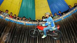 Pengendara motor melakukan akrobat 'Tong setan' di pasar malam PURI BETA II, Tangerang , Banten, Kamis (31/12). Acara ini untuk menghibur masyarakat yang ingin menghabiskan malam tahun baru. (Liputan6.com/Helmi Afandi)