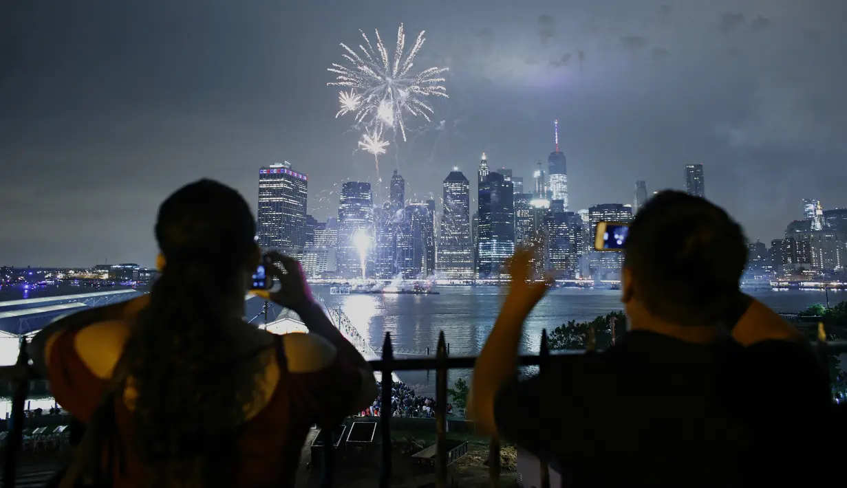 Warga mengambil gambar kembang api yang menghiasi langit kota New York saat perayaan hari kemerdekaan Amerika Serikat (AS) , Senin (4/7). AS merayakan hari ulang tahun kemerdekaan yang ke-240 dari Inggris. (KENA Betancur/AFP)