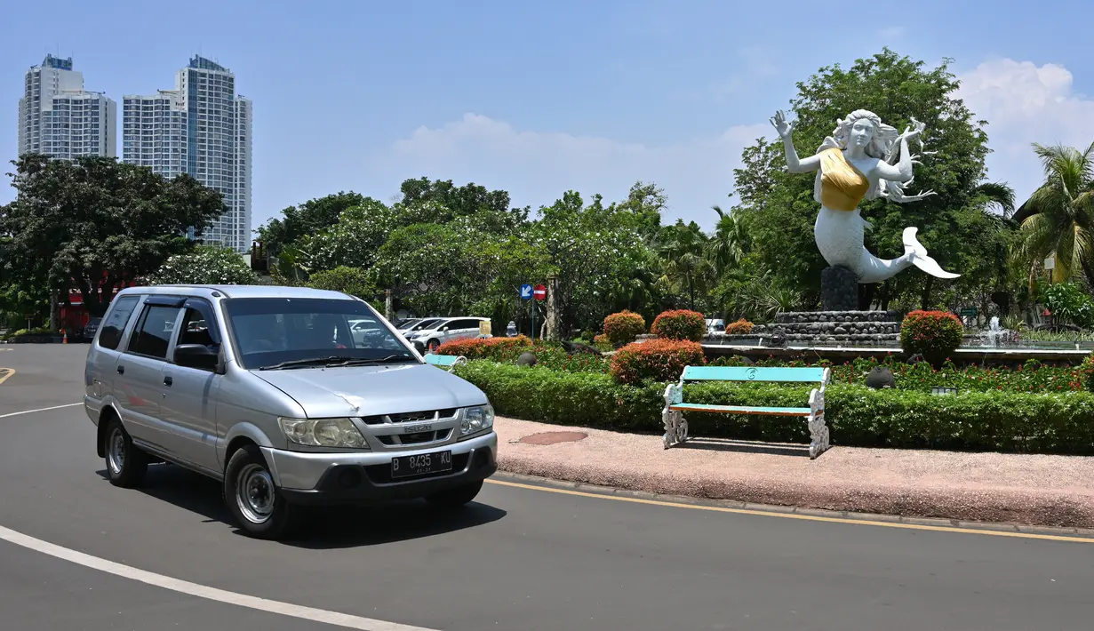 Sebuah mobil melintas dekat patung putri duyung yang bagian dadanya ditutup kain berwarna emas di kawasan Putri Duyung Resort Ancol, Jakarta, Selasa (26/3). Alasan pemakaian kemben pada patung putri duyung itu adalah untuk menyesuaikan dengan budaya ketimuran. (Photo by ADEK BERRY / AFP)