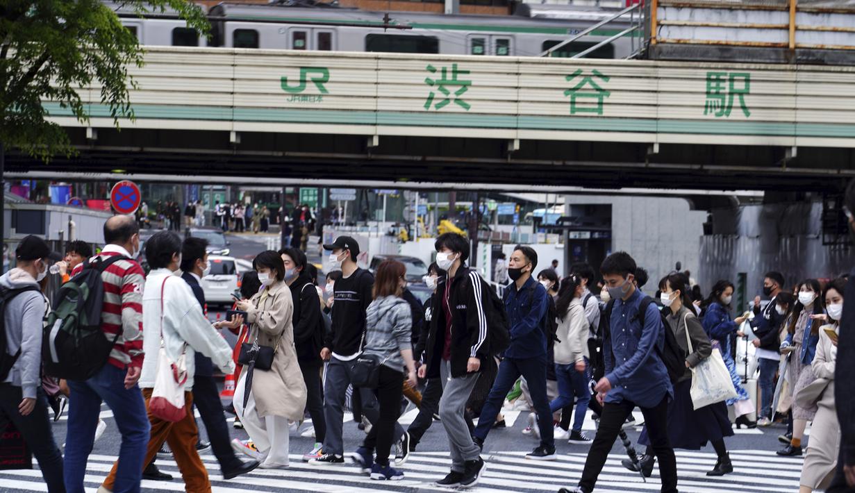 Orang-orang mengenakan masker berjalan melintasi penyeberangan pejalan kaki pada awal liburan "Minggu Emas" Jepang di distrik Shibuya, Tokyo, Kamis (29/4/2021). Golden Week atau Minggu Emas adalah periode di akhir bulan April sampai minggu pertama bulan Mei. (AP Photo/Eugene Hoshiko)