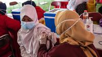 Seorang warga menerima vaksin virus corona COVID-19 Sinovac di pusat vaksinasi massal darurat di lapangan sepak bola di Surabaya, Jawa Timur, Kamis (30/9/2021). Vaksinasi ini dalam rangka percepatan penanganan COVID-19 dan pemulihan ekonomi nasional. (Juni Kriswanto/AFP)