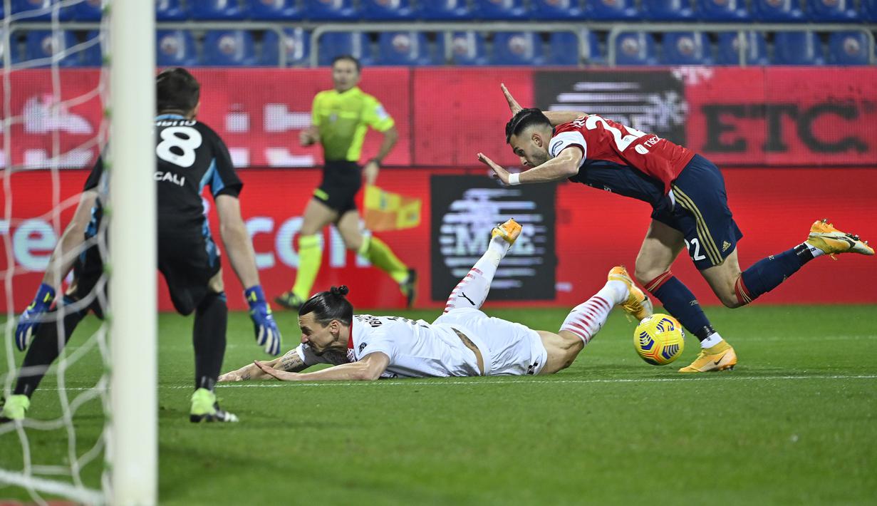 Bek Cagliari, Charis Lykogiannis (kanan) menjatuhkan striker AC Milan, Zlatan Ibrahimovic di dalam kotak penalti dalam laga lanjutan Liga Italia 2020/21 pekan ke-18 di Sardegna Arena, Senin (18/1/2021). Cagliari kalah 0-2 dari AC Milan. (AFP/Alberto Pizzoli)