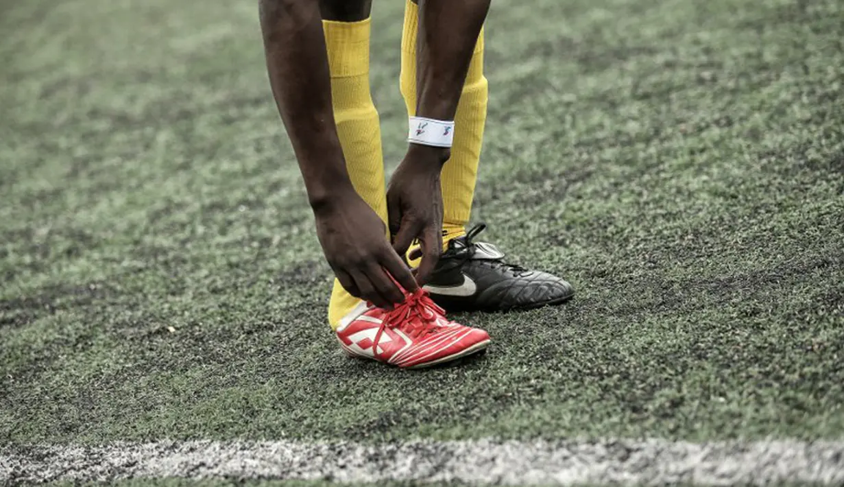 Pemain Mali sedang membenahi tali sepatunya saat bermain melawan Guinea dalam turnamen sepak bola untuk kaum migran dan orang asing bertajuk "Balon Mundial" yang dihelat 6 Juni-5 Juli 2015 di Turin, Italia. (AFP PHOTO/MARCO BERTORELLO)