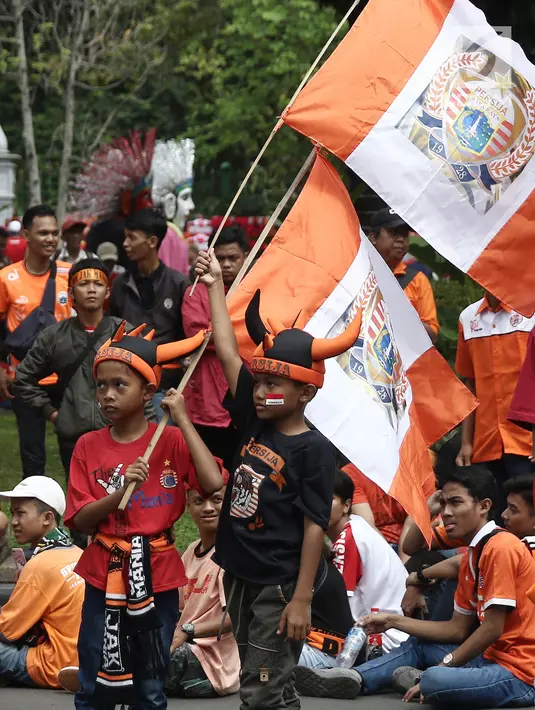Jakmania mengibarkan bendera Persija saat penyerahan piala Liga I di depan Balai Kota, Jakarta, Sabtu (15/12). Kemenangan Persija di Liga 1 jadi momen bersejarah bagi masyarakat Ibu Kota. (Liputan6.com/Herman Zakharia)