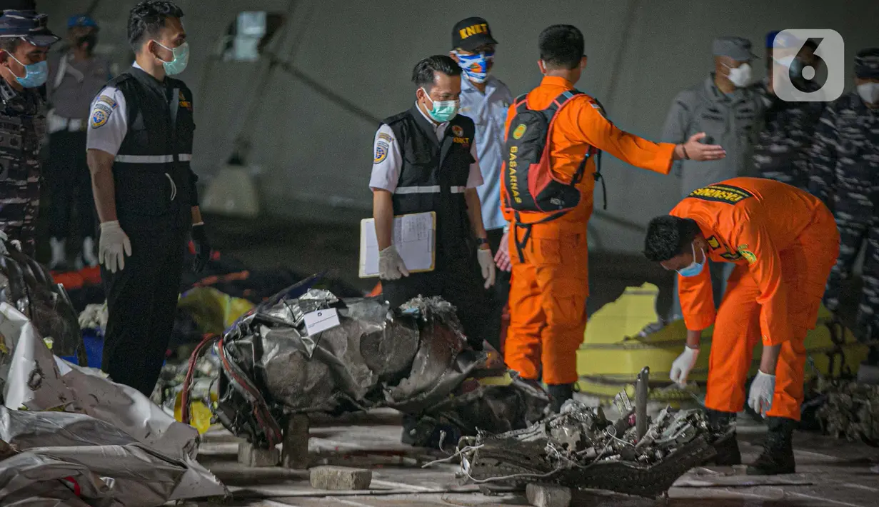 Petugas Basarnas mengumpulkan puing pesawat Sriwijaya Air nomor penerbangan SJ 182 rute Jakarta-Pontianak pada hari ketujuh operasi SAR pesawat tersebut di JICT II Tanjung Priok, Jakarta Utara, Jumat (15/1/2021). (Liputan6.com/Faizal Fanani)