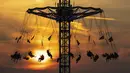 Sejumlah orang mengendarai komidi putar saat matahari terbenam di Taman Olimpiade, Munich, Jerman, 12 Agustus 2020. (Sven Hoppe/dpa via AP)