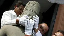 Petugas menyambungkan kepala patung dewa Hindu dari abad ke-7 ke tubuhnya pada upacara di Museum Nasional Kamboja, Kamis (21/1). Prancis mengembalikan kepala patung dewa Harihara setelah diambil lebih dari 130 tahun yang lalu. (REUTERS/Samrang Pring)