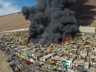 Rumah-rumah terbakar selama kebakaran di lingkungan berpenghasilan rendah Laguna Verde, di Iquique, Chili, Senin (10/1/2022). Menurut pihak berwenang, api menghanguskan hampir 100 rumah di lingkungan itu yang sebagian besar dihuni oleh para migran. (AP Photo/Ignacio Munoz)