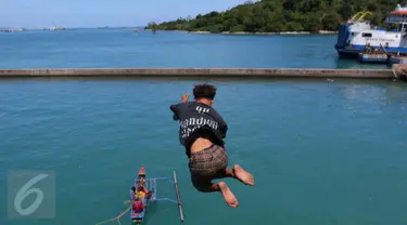 Seorang anak melompat ke laut ketika penumpang melemparkan koin dari atas kapal di Pelabuhan Merak, Banten, Jumat (26/8). Aksi anak-anak pemburu koin itu menjadi hiburan bagi penumpang yang akan menyeberang ke Pulau Sumatera. (Liputan6.com/Angga Yuniar)